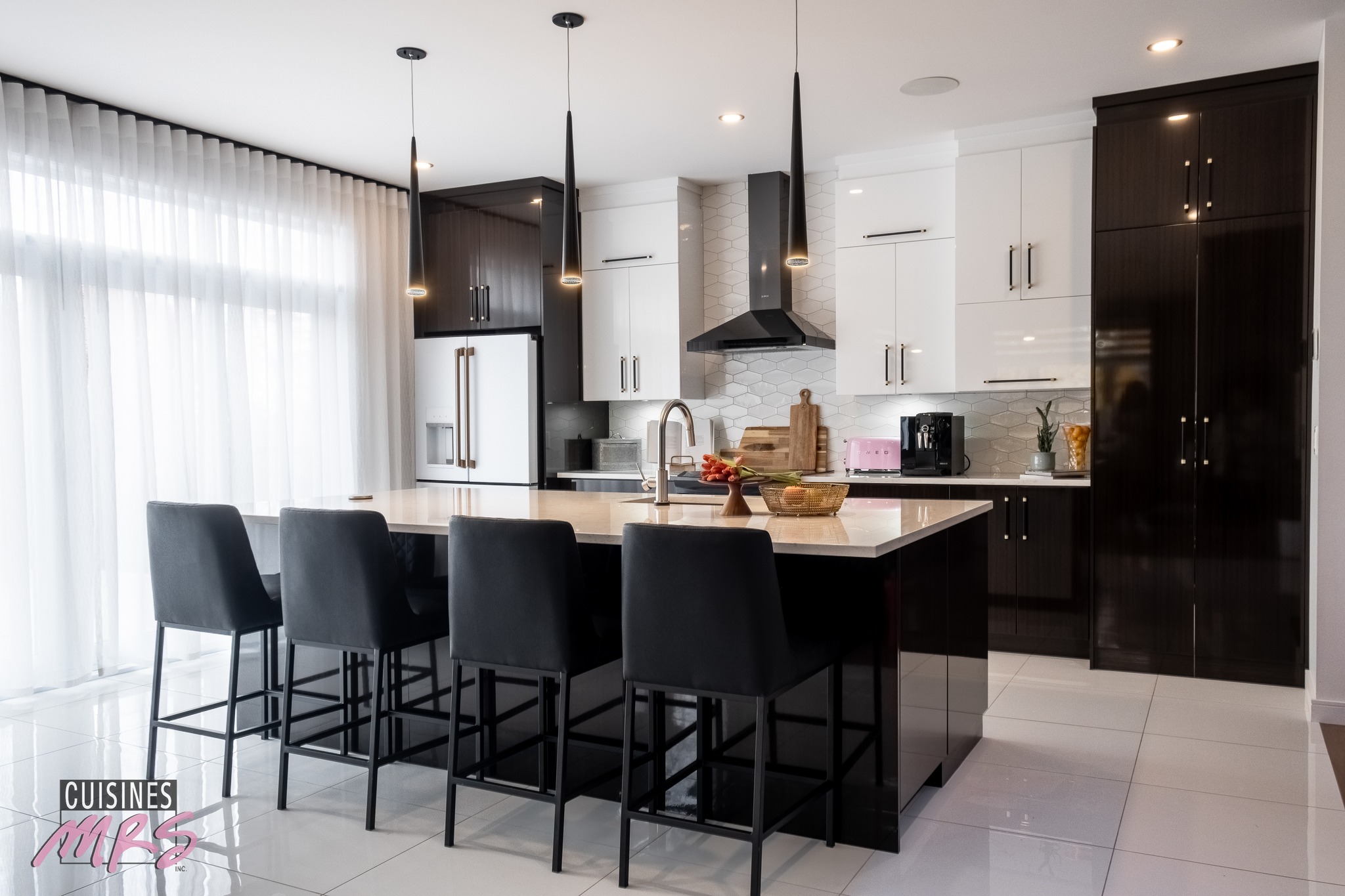Cuisine moderne avec un grand îlot doté de quatre chaises noires, des armoires blanches, des touches de bois foncé, des appareils en acier inoxydable, des lampes suspendues et une fenêtre avec des rideaux transparents qui laissent entrer la lumière naturelle.